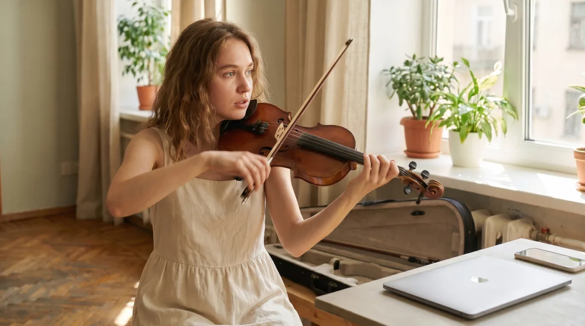 A young violinist mid-play, bow drawn across the strings, in a sunlit apartment with sheet music spread across the table
