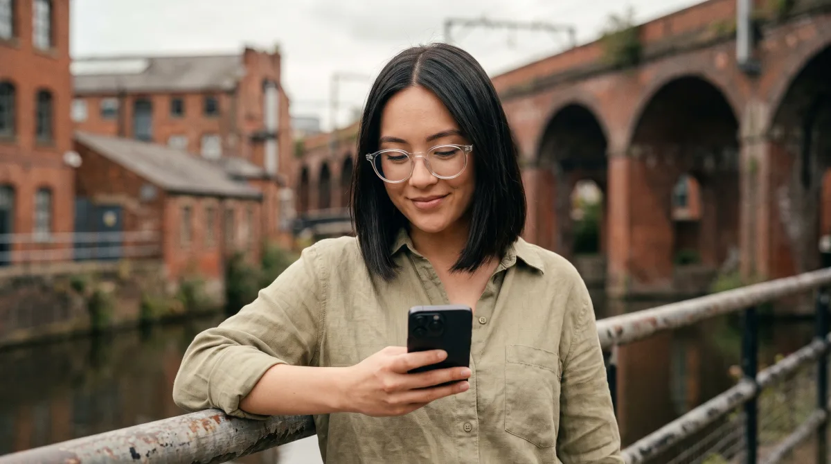 A young woman by a Manchester canal in summer checking her phone