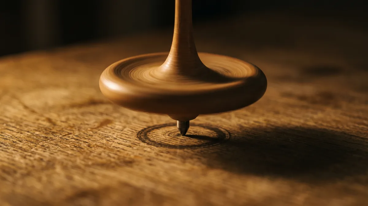 A wooden spinning top mid-rotation on a table, its rim blurred with motion under low warm side light