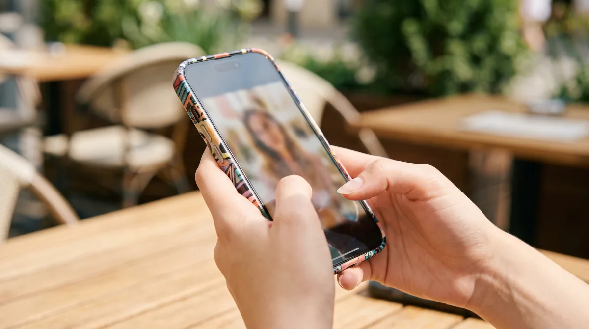Close-up of young hands holding a phone showing an obscured, partly hidden photo of a person