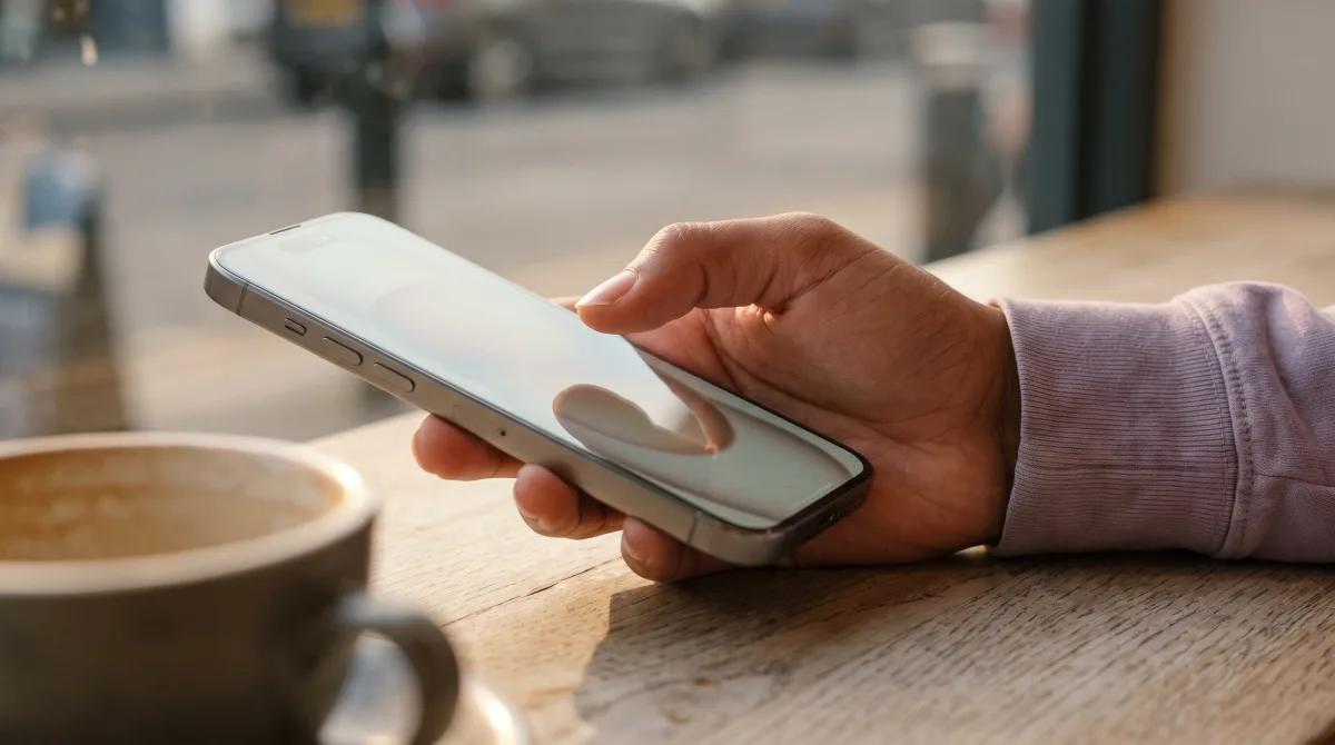 A thumb hovering motionless just above a phone screen, the display blurred past reading